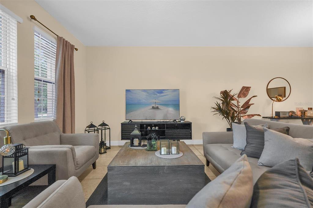 A living room features gray sofas, a large wooden coffee table, and a television console — 12353 VIA DERNA PLACE, WINDERMERE, FL