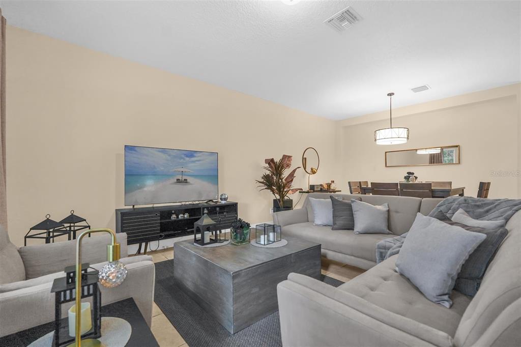 A living room features a gray sectional sofa, a coffee table, and a television console — 12353 VIA DERNA PLACE, WINDERMERE, FL