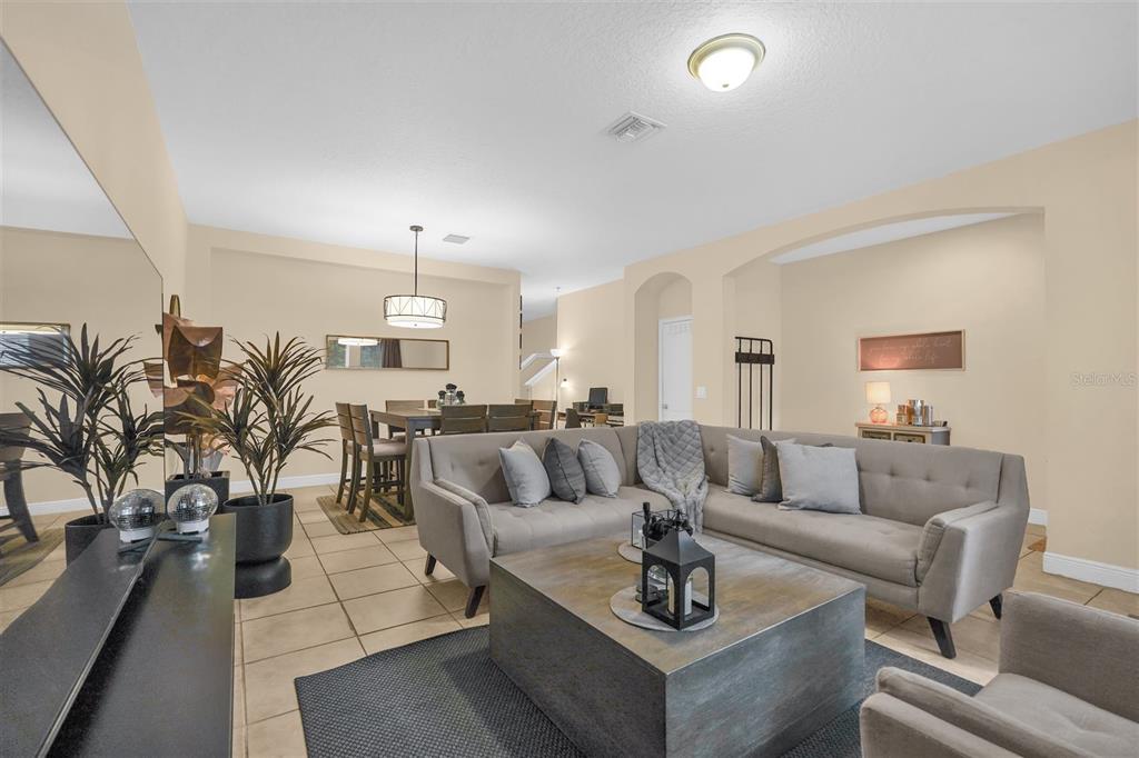 A living room and dining area with tile flooring, a gray sectional sofa, and neutral walls — 12353 VIA DERNA PLACE, WINDERMERE, FL