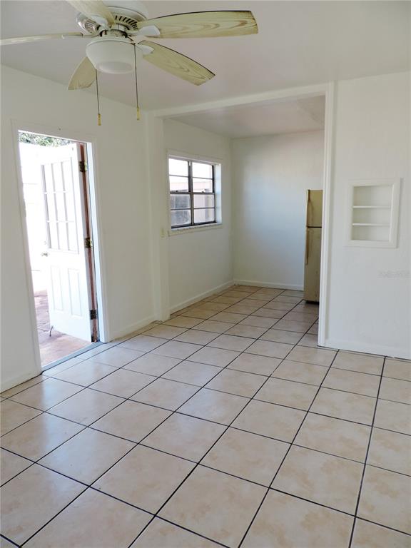 A room with tiled floors, a ceiling fan, and an open doorway leading to a kitchen — 12127 GULF BOULEVARD UNIT 1, TREASURE ISLAND, FL