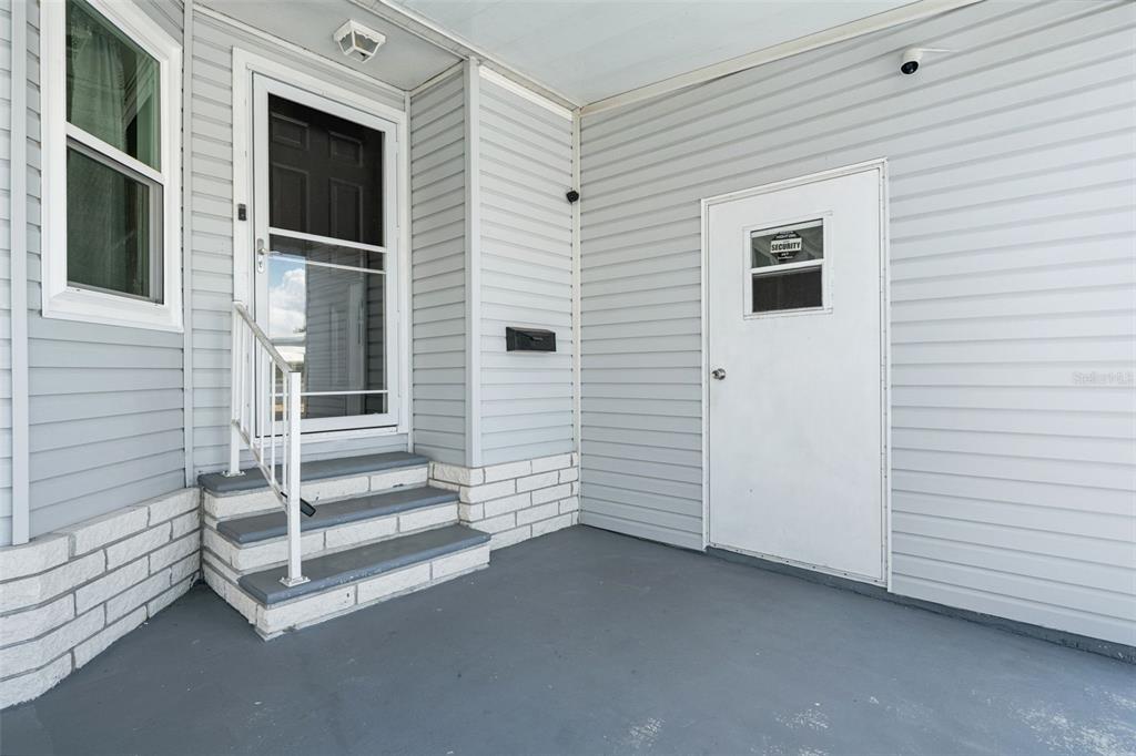 A covered porch features gray siding, a set of stairs with a railing, and two doors — 116 MOUNT ISLE AVENUE NE UNIT 116, ST PETERSBURG, FL