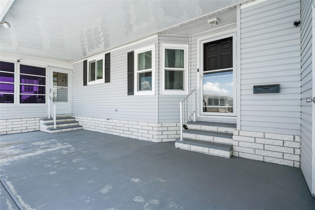 A covered patio with gray concrete flooring, light gray siding, and two sets of entry stairs — 116 MOUNT ISLE AVENUE NE UNIT 116, ST PETERSBURG, FL