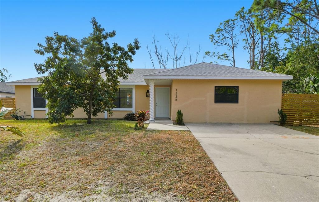 A single-story house with a yellow stucco exterior, a concrete driveway, and a front porch — 1336 GINGOLD STREET NW, PALM BAY, FL