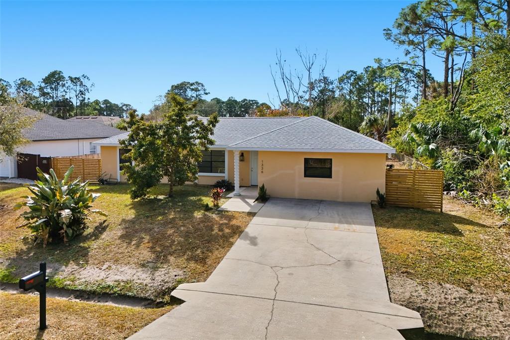 A single-story, light-yellow house with a concrete driveway and a gray shingled roof — 1336 GINGOLD STREET NW, PALM BAY, FL