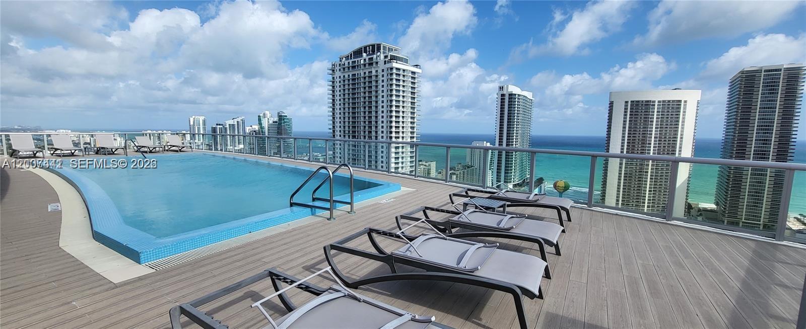 A rooftop swimming pool overlooks the ocean and surrounding high-rise buildings from a wooden deck — 2602 E Hallandale Beach Blvd # R306, Hallandale Beach FL 33009, HALLANDALE BEACH, FL