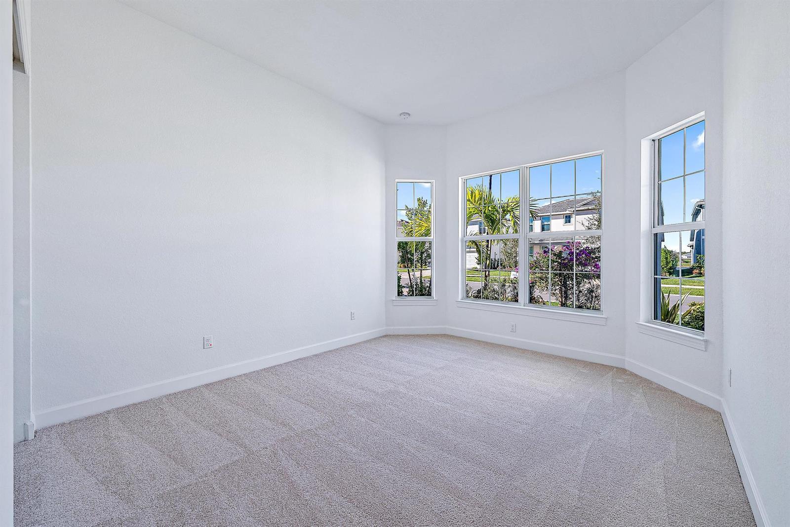 An empty bedroom features white walls, beige carpeting, and a bay window with exterior views — 9775 SW Meridian Way, Stuart FL 34997, STUART, FL