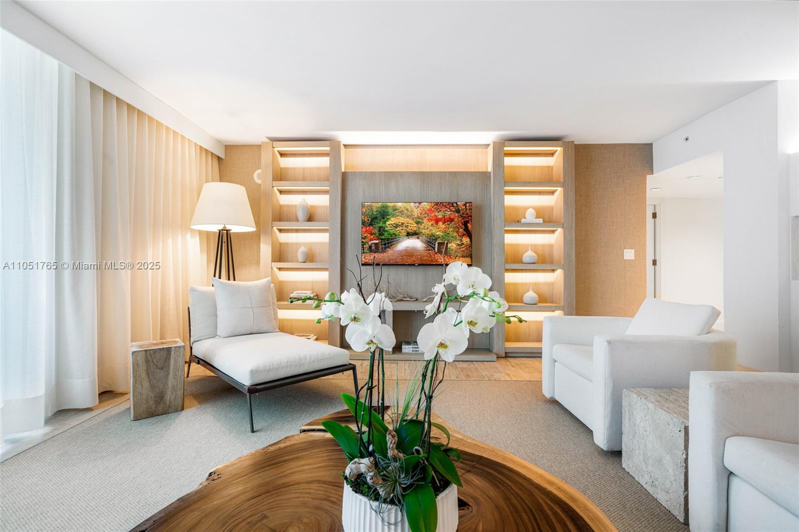 A living room features a television, built-in shelving, white furniture, and a wooden coffee table — 102 24th St # 1115, Miami Beach FL 33139, MIAMI BEACH, FL