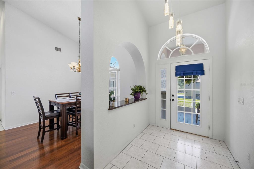 A tiled entryway leads to a dining room with wood floors and an arched cutout — 23530 CLAY AVENUE, PORT CHARLOTTE, FL