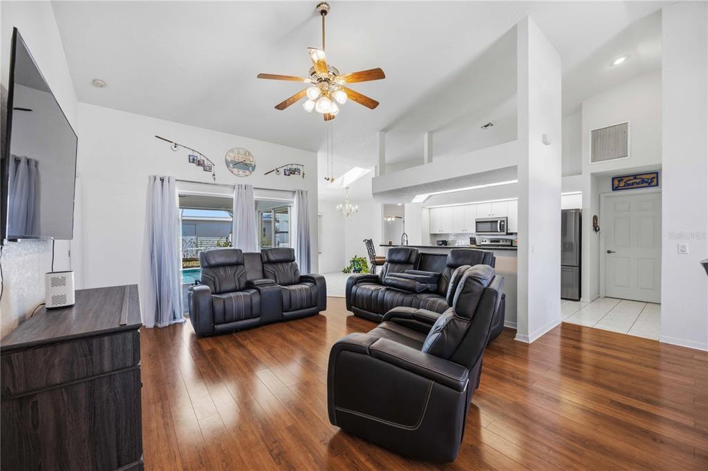 A living room with wood flooring, dark leather furniture, and an open kitchen in back — 23530 CLAY AVENUE, PORT CHARLOTTE, FL
