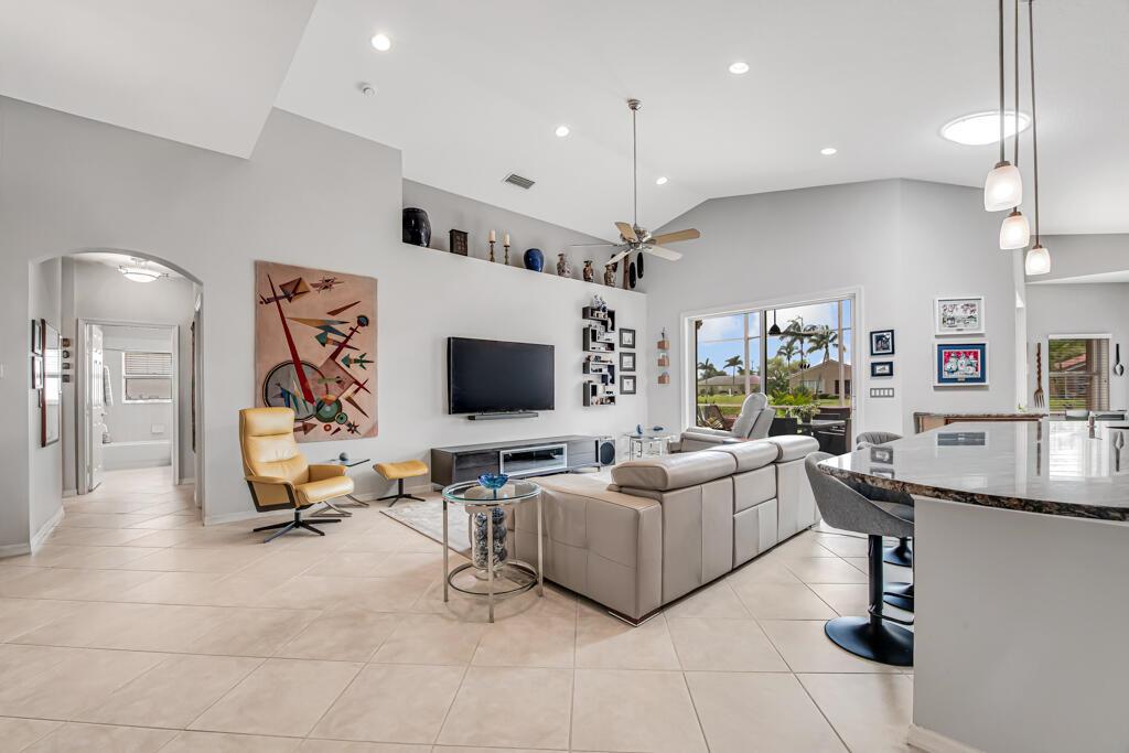 A spacious living room features a vaulted ceiling, tile flooring, a large sectional, and television — 8417 Grand Messina Circle, Boynton Beach FL 33472, BOYNTON BEACH, FL