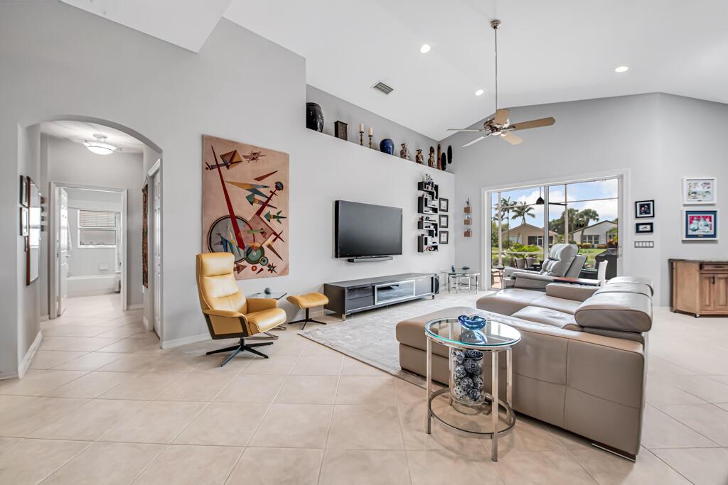 A spacious living room features a large television, leather seating, and a view of a pool — 8417 Grand Messina Circle, Boynton Beach FL 33472, BOYNTON BEACH, FL