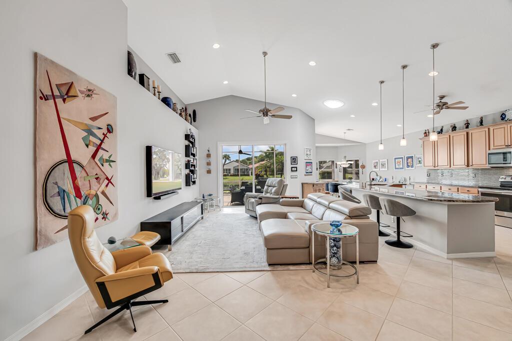 An open-concept living room and kitchen feature tile floors, a sectional sofa, and vaulted ceilings — 8417 Grand Messina Circle, Boynton Beach FL 33472, BOYNTON BEACH, FL
