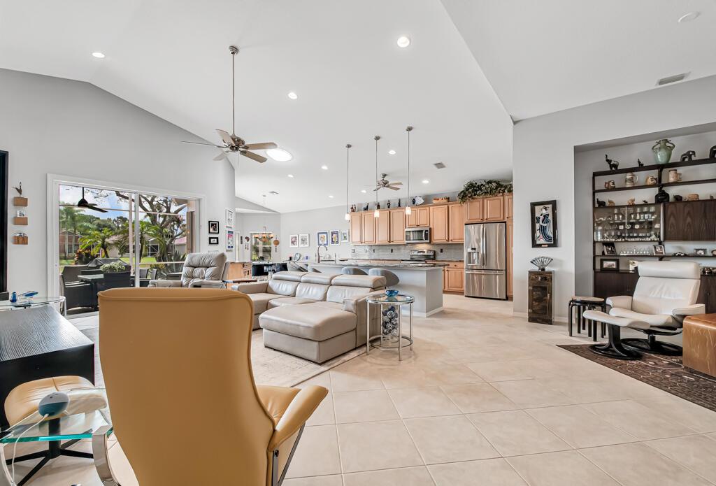 An open-concept living room and kitchen featuring light tile floors, vaulted ceilings, and neutral walls — 8417 Grand Messina Circle, Boynton Beach FL 33472, BOYNTON BEACH, FL