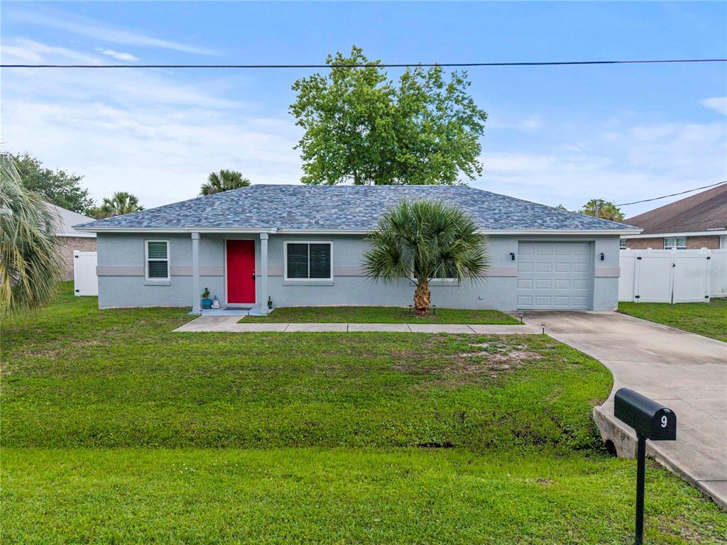 A single-story gray house with a red front door, a garage, and a front lawn — 9 BILTWELL PLACE, PALM COAST, FL