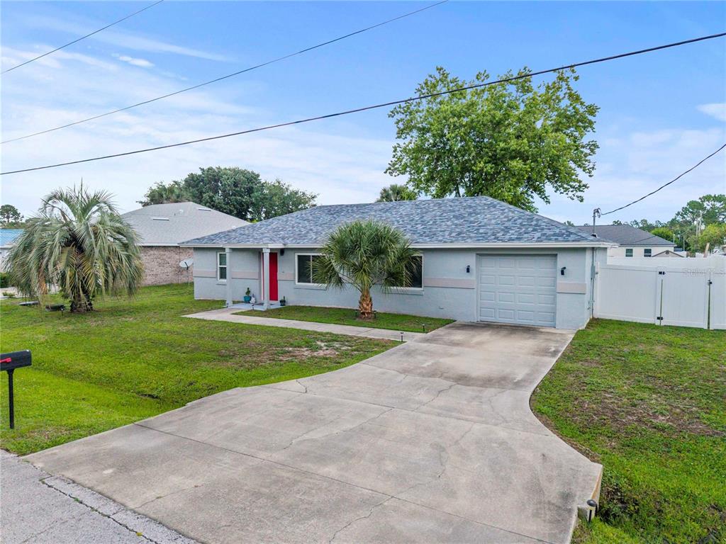 A single-story house with a gray exterior, a red front door, and a concrete driveway — 9 BILTWELL PLACE, PALM COAST, FL