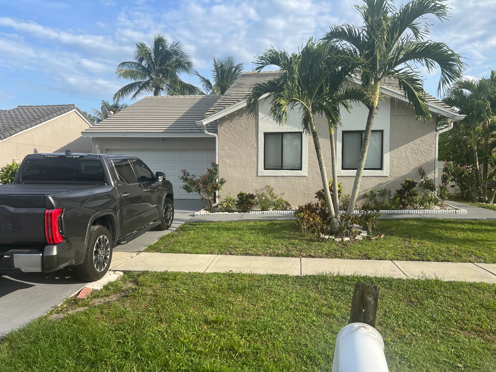 A single-story house with a beige stucco exterior, a gray tile roof, and palm trees — 5765 Strawberry Lakes Circle, Lake Worth FL 33463, LAKE WORTH, FL