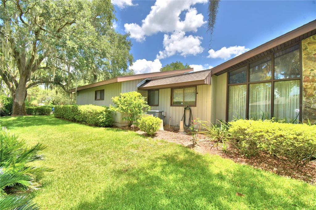 The exterior of a house features vertical siding, large windows, and a landscaped yard — 20 NOTTINGHAM WAY, HAINES CITY, FL