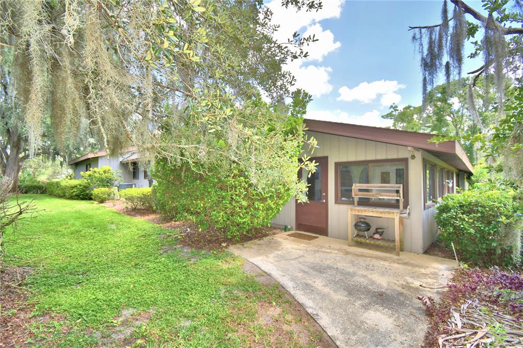 A concrete patio sits outside a single-story house with gray siding and a brown door — 20 NOTTINGHAM WAY, HAINES CITY, FL