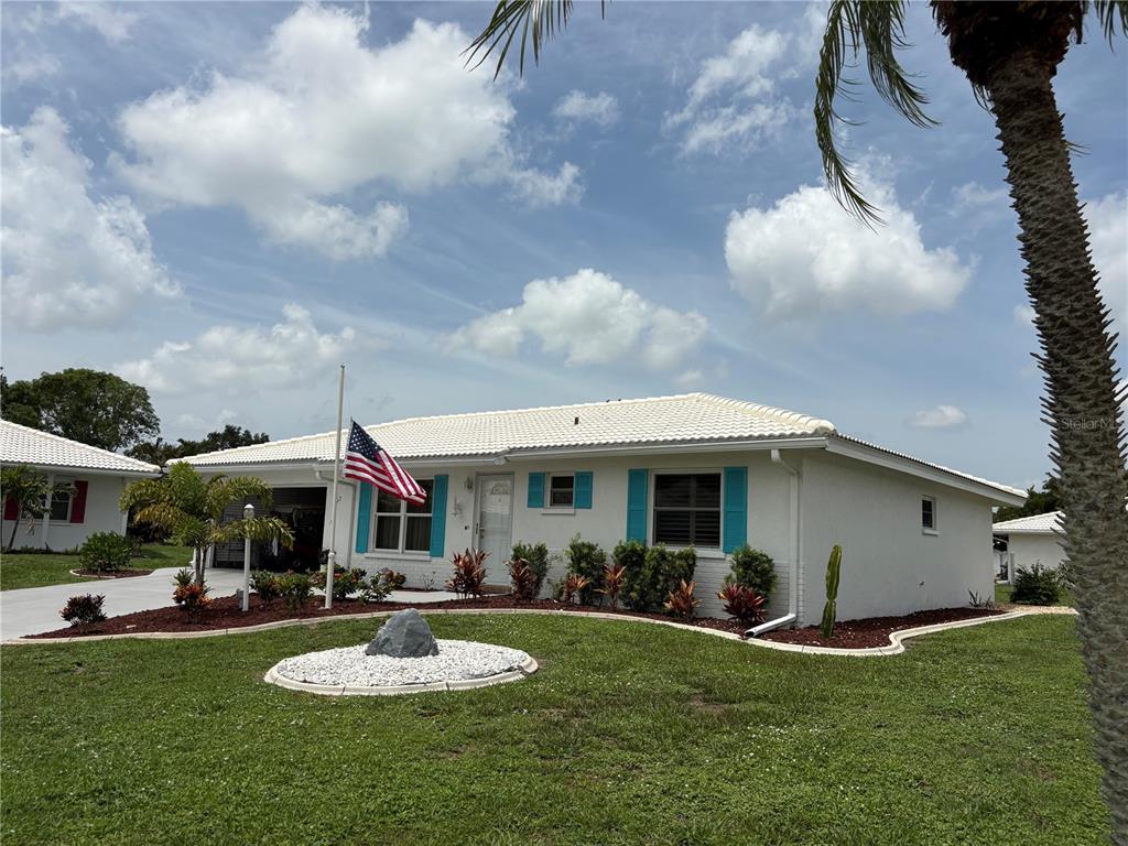 A white single-story house with blue shutters and a tiled roof sits on a lawn — 1612 S ELMWOOD DRIVE, BRADENTON, FL