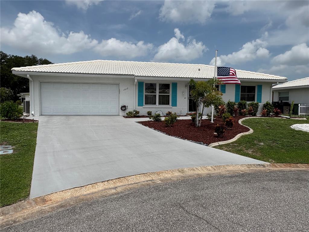 A single-story house with a white exterior, a tiled roof, and a concrete driveway — 1612 S ELMWOOD DRIVE, BRADENTON, FL