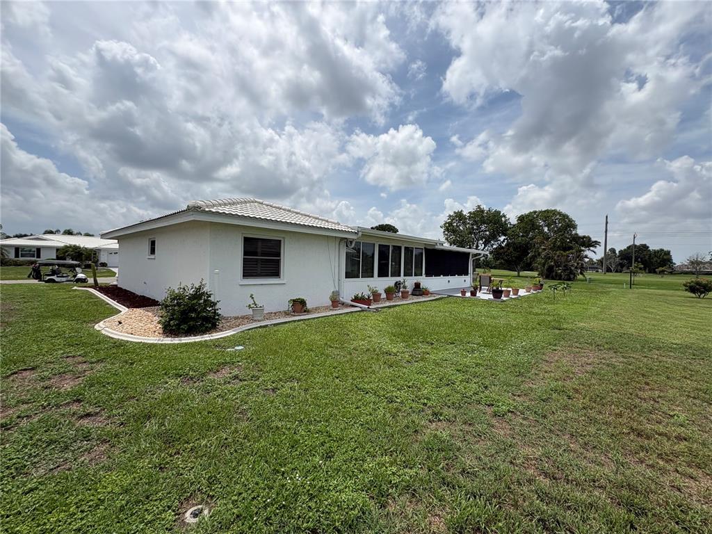 The exterior of a white house with a screened-in patio sits on a grassy lot — 1612 S ELMWOOD DRIVE, BRADENTON, FL