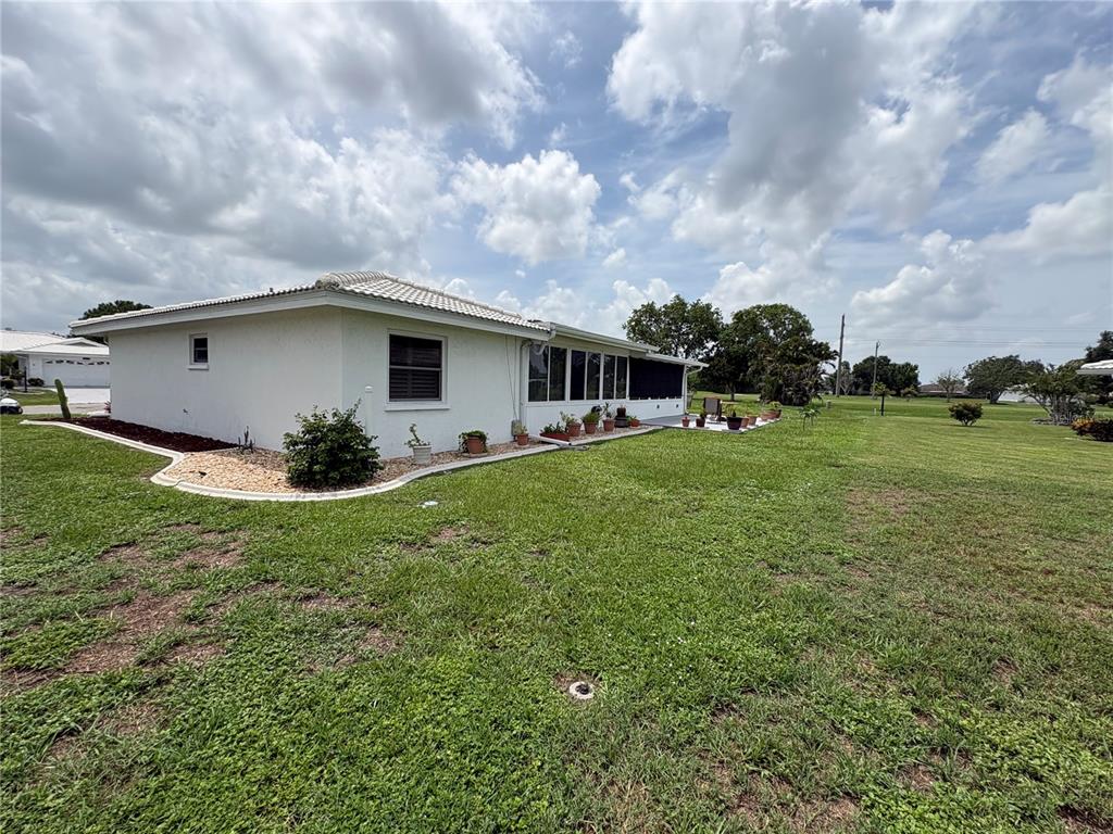 The exterior of a white, single-story house features a landscaped garden bed and a lawn — 1612 S ELMWOOD DRIVE, BRADENTON, FL