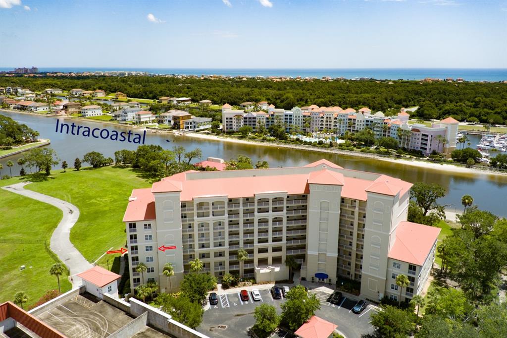 An aerial view shows a multi-story apartment building near a waterway and the ocean — 146 PALM COAST RESORT BOULEVARD UNIT 501, PALM COAST, FL