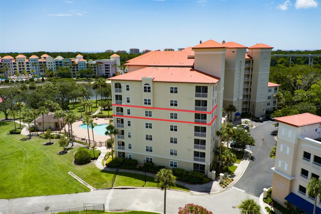 An aerial view of a multi-story apartment building with a pool and surrounding landscape — 146 PALM COAST RESORT BOULEVARD UNIT 501, PALM COAST, FL