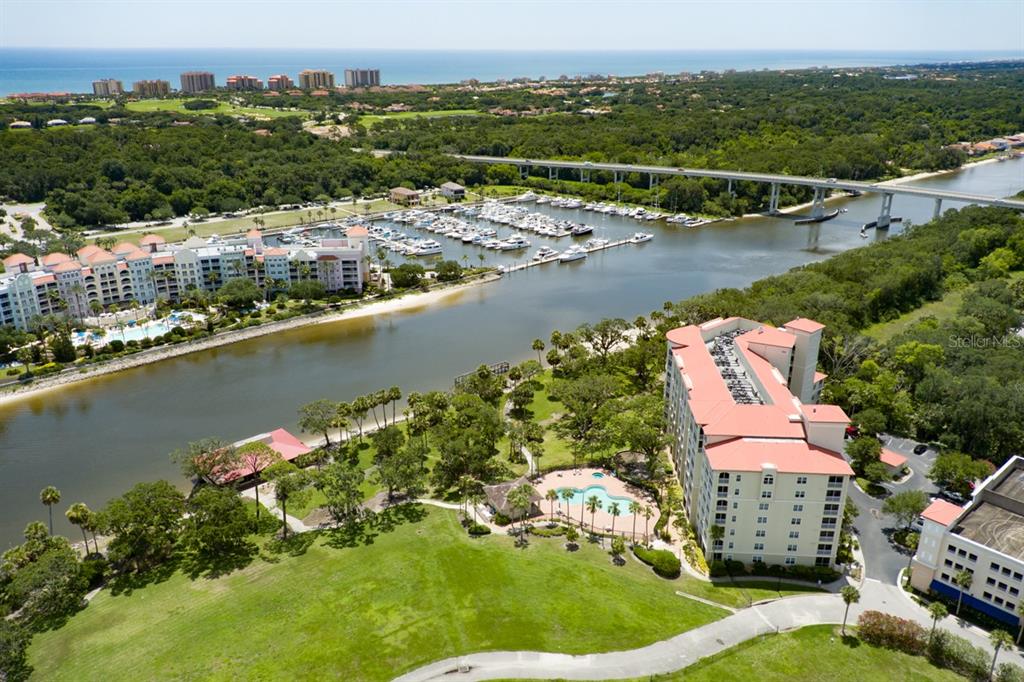 An aerial view shows a multi-story building, a swimming pool, a marina, and a bridge — 146 PALM COAST RESORT BOULEVARD UNIT 501, PALM COAST, FL