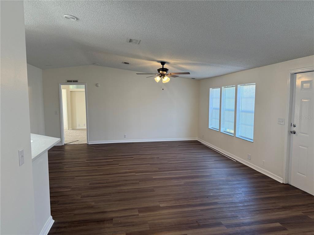 An empty living room features wood-look flooring, a ceiling fan, and three windows — 4795 SCHOONER AVENUE, LAKE WALES, FL