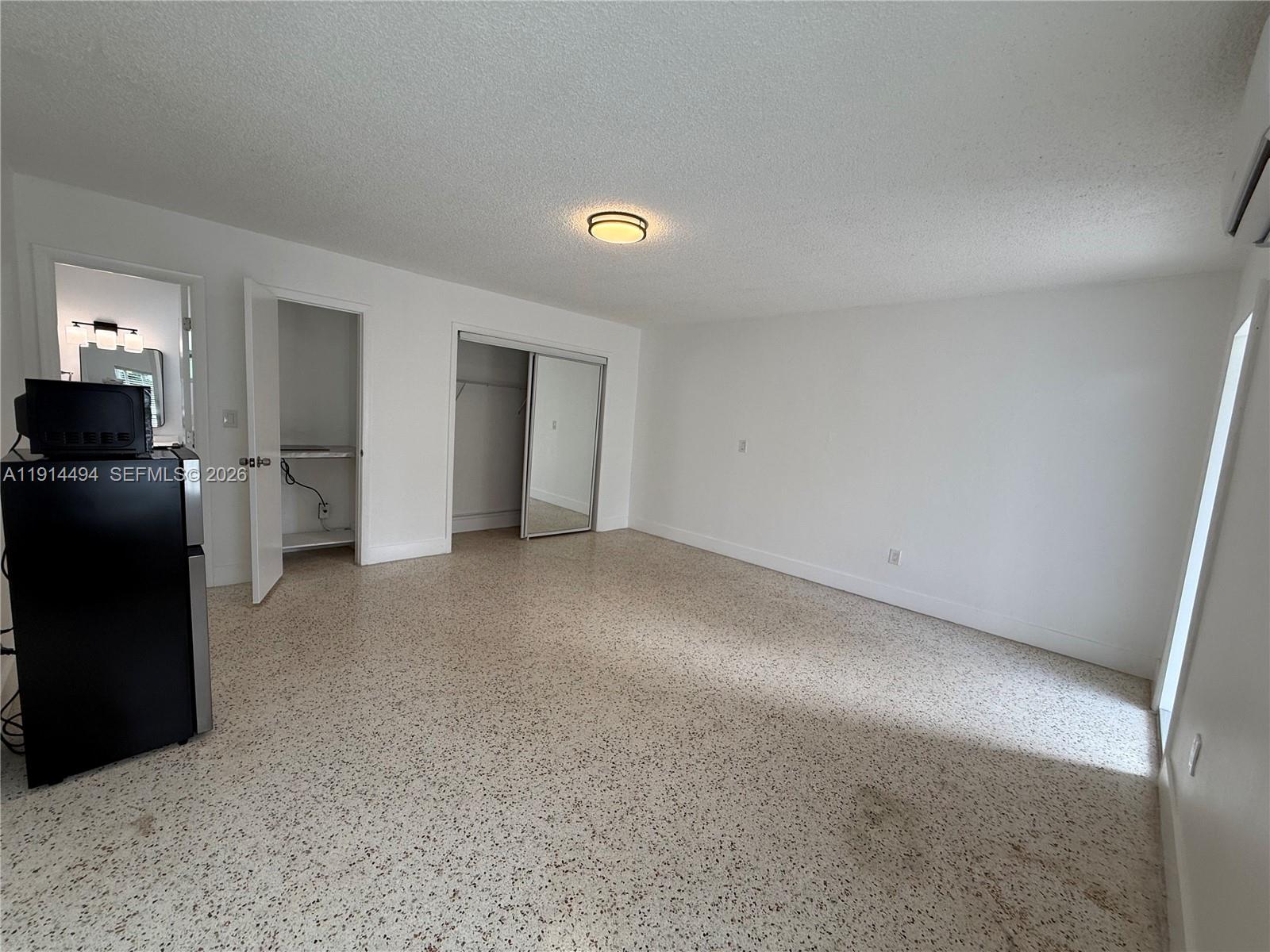 This bedroom features white walls, a speckled floor, a ceiling light, and two closets — 3144 NW 29th St # 2, Miami FL 33142, MIAMI, FL