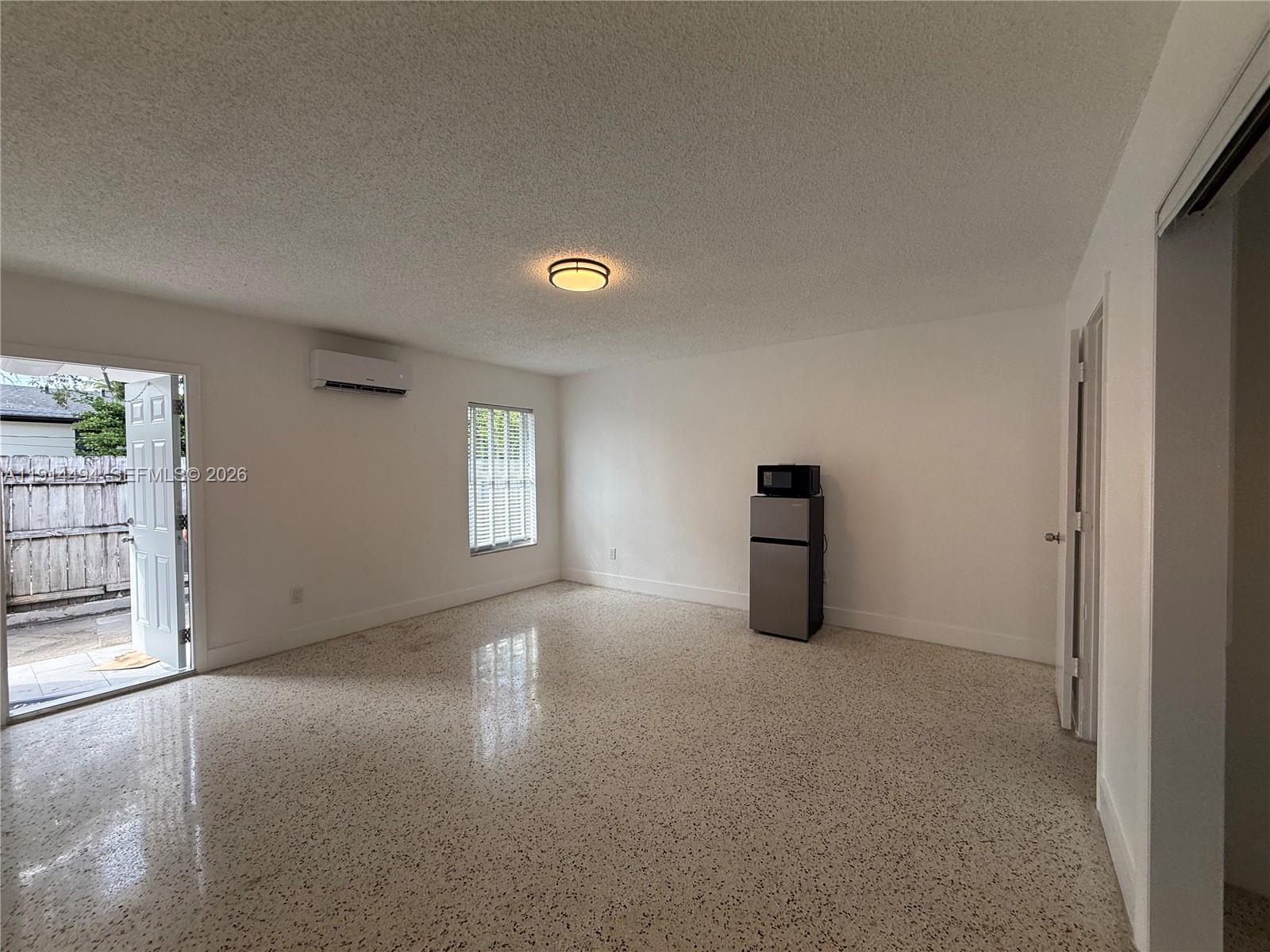 A room with terrazzo flooring, a mini-fridge, a ceiling light, and an exterior door — 3144 NW 29th St # 2, Miami FL 33142, MIAMI, FL