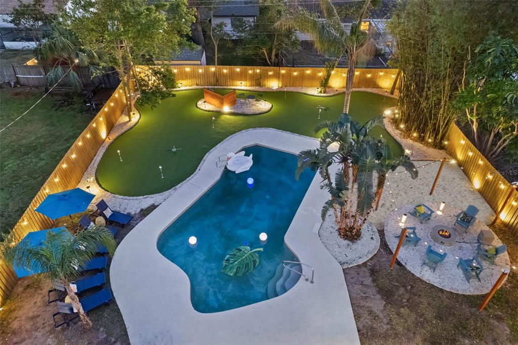 An aerial view of a backyard featuring a swimming pool, putting green, and fire pit area — 13672 88TH AVENUE, SEMINOLE, FL