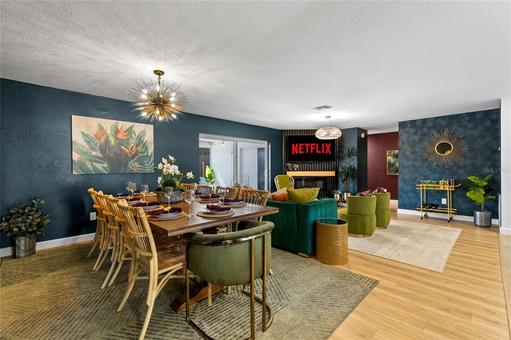 An open-concept dining and living area features dark blue walls, wood flooring, and green furniture — 13672 88TH AVENUE, SEMINOLE, FL