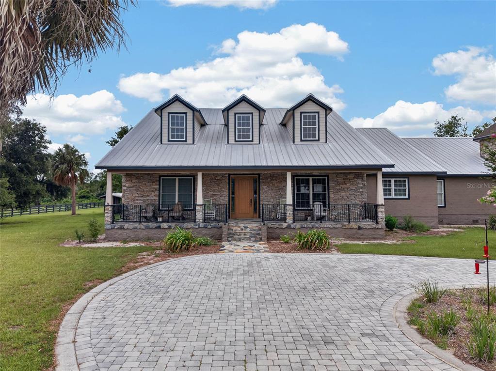 A stone-faced house with a metal roof, three dormers, and a paved circular driveway — 13342 W LAKE YALE ROAD, UMATILLA, FL