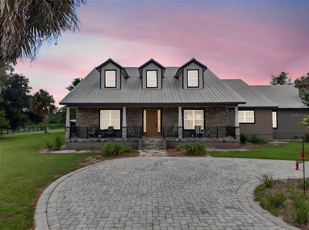 A stone-faced house with a metal roof and dormer windows sits behind a paved driveway — 13342 W LAKE YALE ROAD, UMATILLA, FL