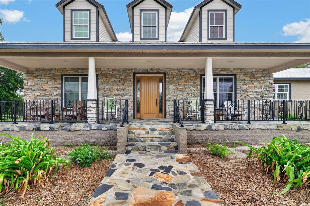 A stone-faced house features a covered porch, a flagstone walkway, and three dormer windows — 13342 W LAKE YALE ROAD, UMATILLA, FL