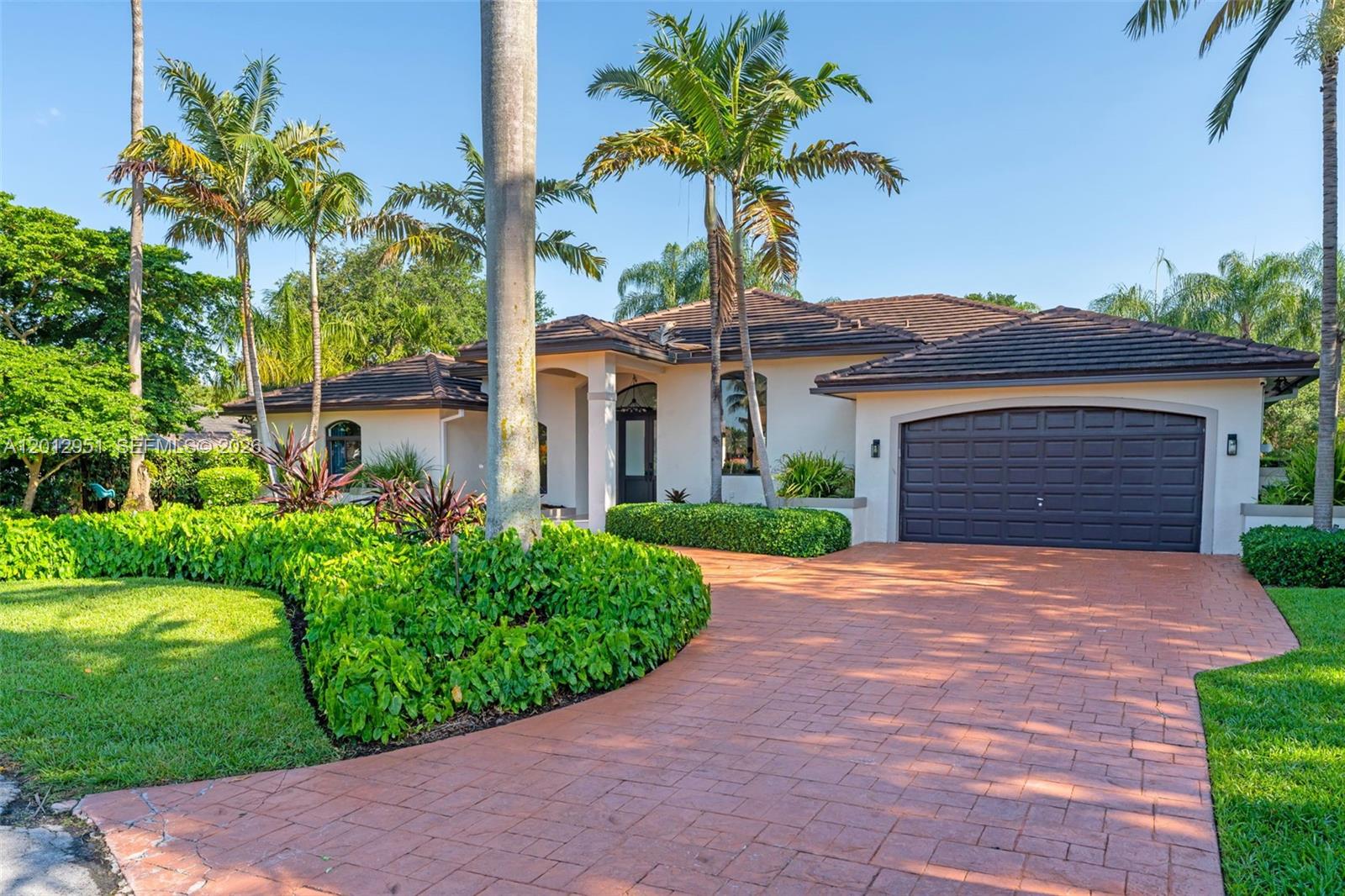 A single-story house with a brown tile roof, a dark garage door, and a paved driveway — 12019 SW 77th Ter, Miami FL 33183, MIAMI, FL