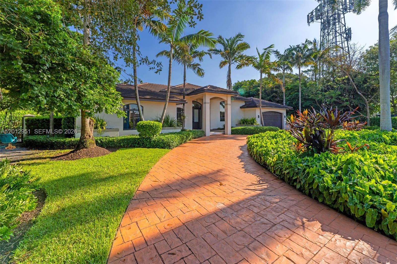 A single-story house with a paved driveway, palm trees, and a large cell tower nearby — 12019 SW 77th Ter, Miami FL 33183, MIAMI, FL