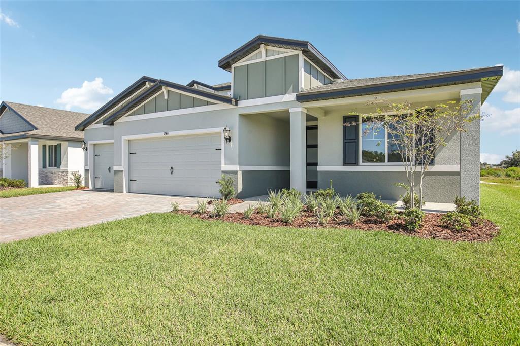A single-story house with a two-car garage, light green stucco siding, and a paved driveway — 1740 DRAUGHTON DRIVE, ZEPHYRHILLS, FL