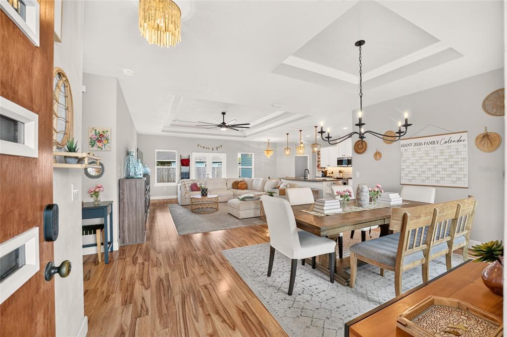 An open-concept living and dining area features wood flooring, a coffered ceiling, and neutral walls — 23038 NW 4TH PLACE, NEWBERRY, FL
