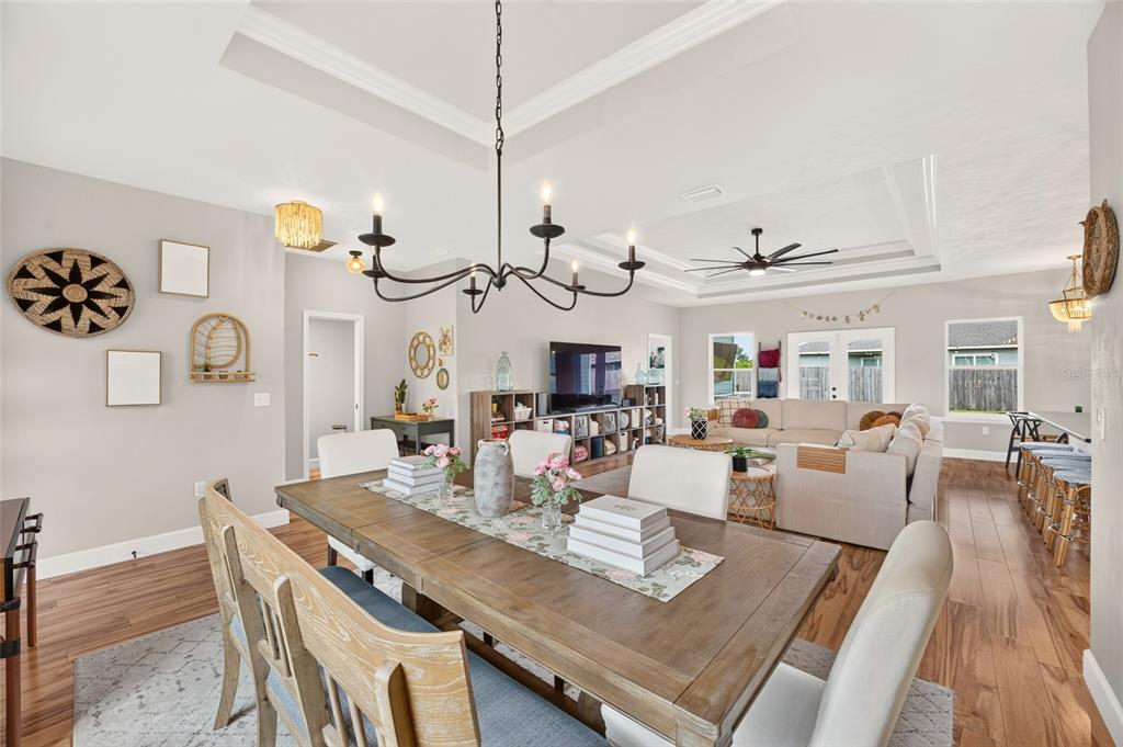 A dining room with a wooden table and chandelier opens into a living area — 23038 NW 4TH PLACE, NEWBERRY, FL