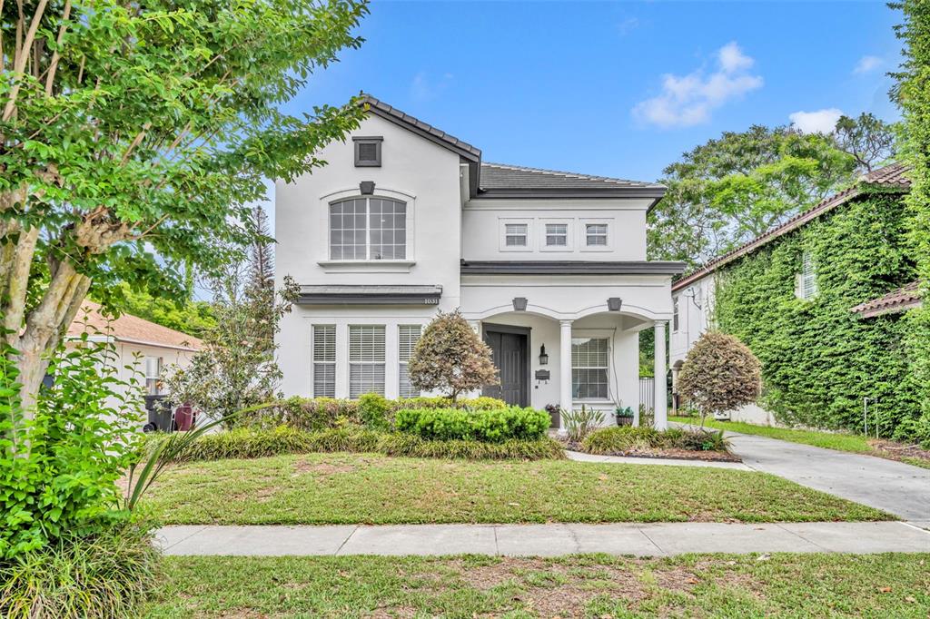 A two-story white house with a covered front porch and a paved driveway — 1031 GUERNSEY STREET, ORLANDO, FL