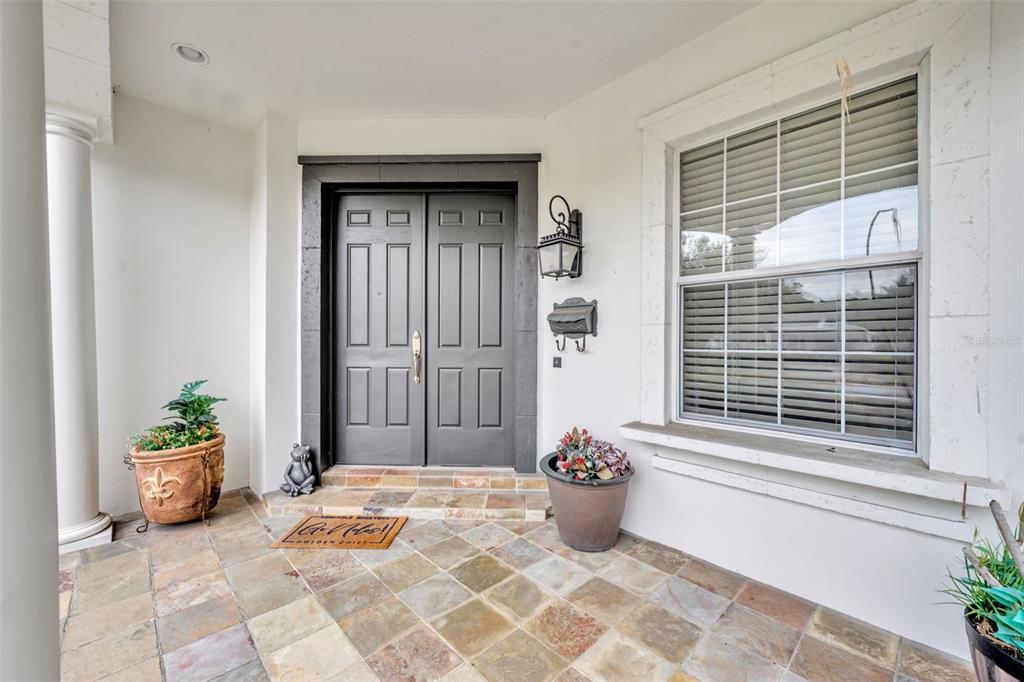 A covered entryway features a dark double door, tiled flooring, and potted plants — 1031 GUERNSEY STREET, ORLANDO, FL