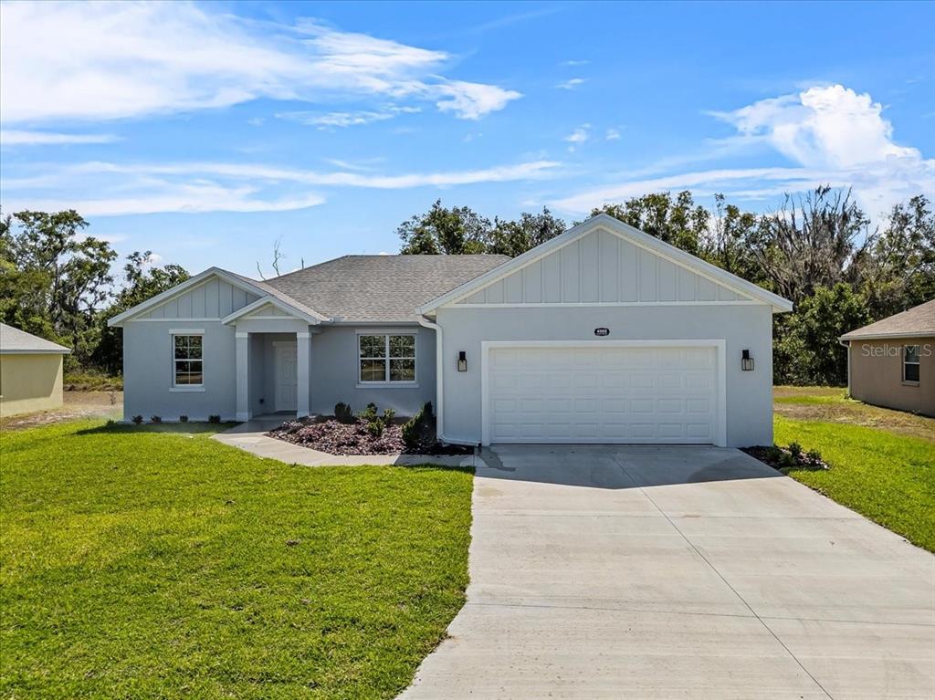 A light gray, single-story suburban house features a two-car garage and a concrete driveway — 4502 FAIRWAY OAKS DRIVE, MULBERRY, FL