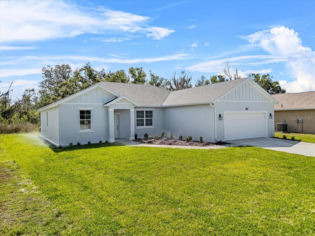 A single-story house with light gray stucco siding, a two-car garage, and a grassy lawn — 4502 FAIRWAY OAKS DRIVE, MULBERRY, FL