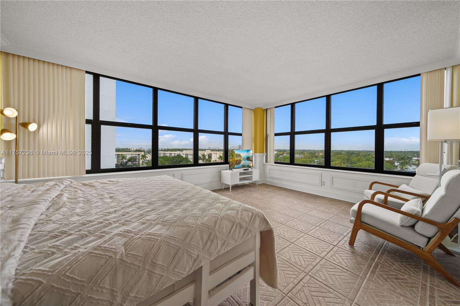 A bedroom features large windows, tiled floors, a bed, and two chairs — 2500 Parkview Dr # 812, Hallandale Beach FL 33009, HALLANDALE BEACH, FL