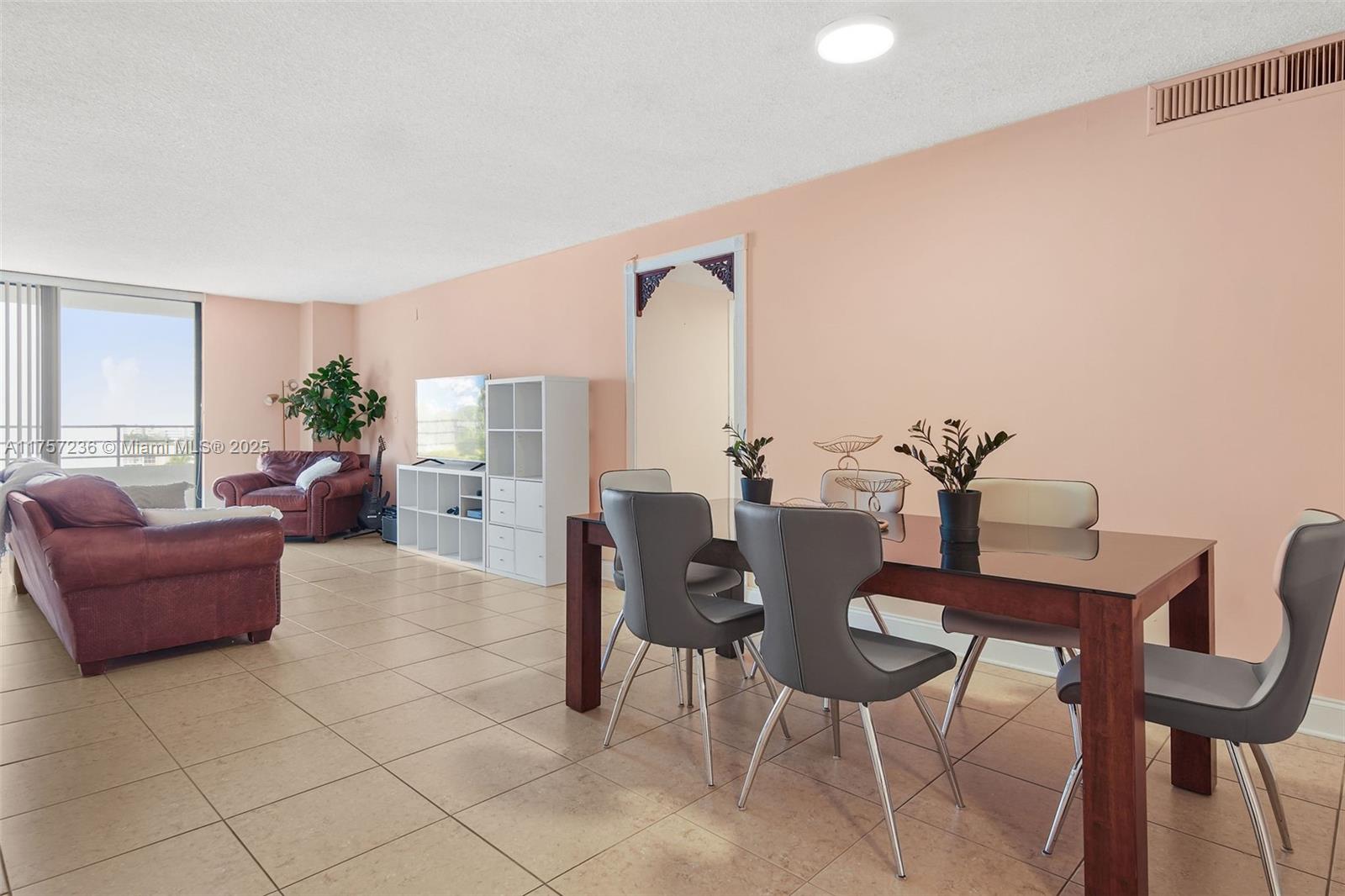A dining area and living room feature tile floors, peach walls, and a glass-topped table — 2500 Parkview Dr # 812, Hallandale Beach FL 33009, HALLANDALE BEACH, FL