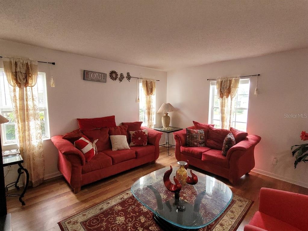 A living room features two red sofas, a glass coffee table, and patterned area rug — 5891 SIR HENRY ROAD, ORLANDO, FL