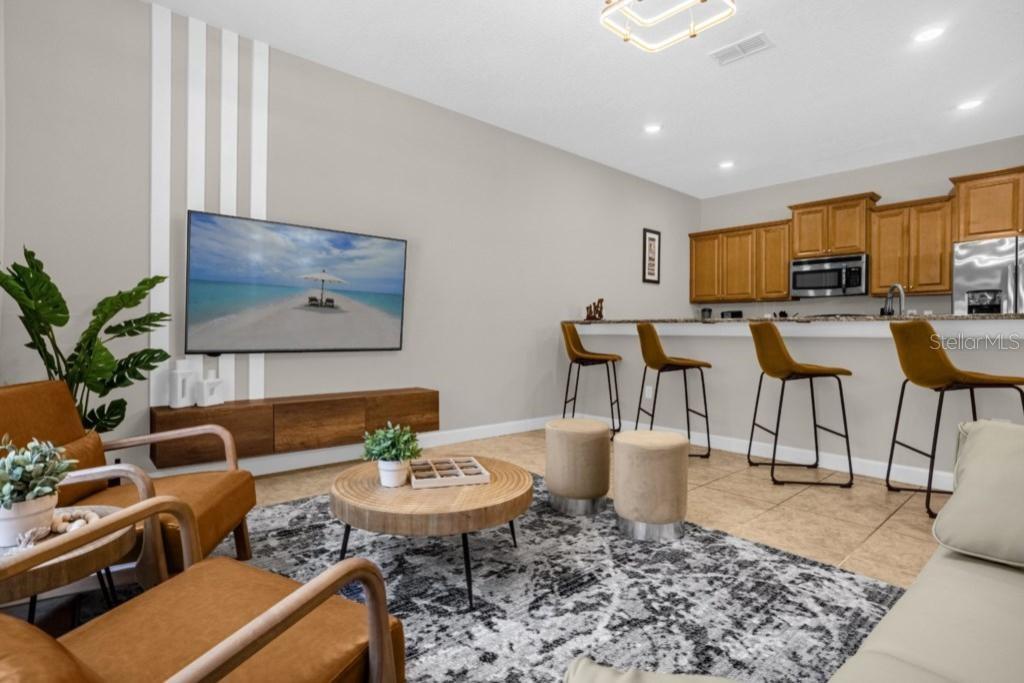 A living room with a wall-mounted television, wooden console, and breakfast bar with four stools — 2955 BANANA PALM DRIVE, KISSIMMEE, FL